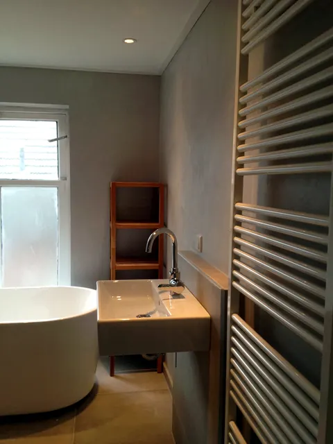 Afgewerkte badkamer in Ulft met vrijstaand bad, wastafel en designradiator